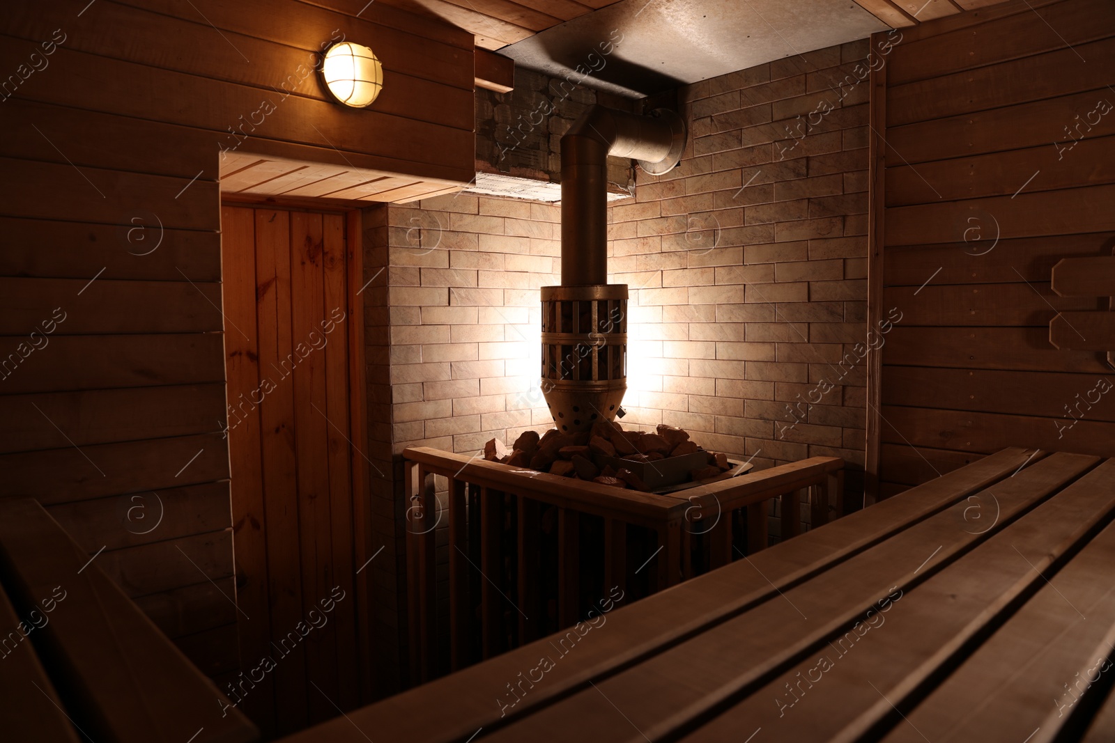 Photo of Wooden sauna with bench, stove and hot stones