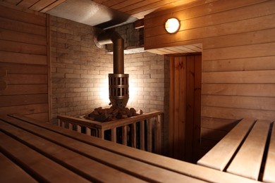 Photo of Wooden sauna with bench, stove and hot stones