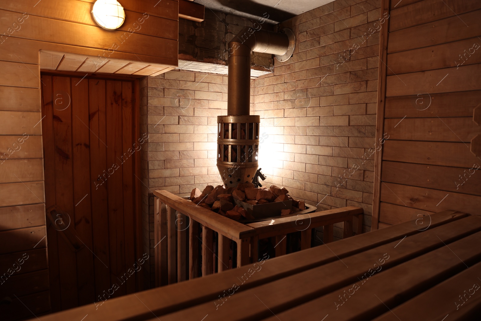 Photo of Wooden sauna with bench, stove and hot stones