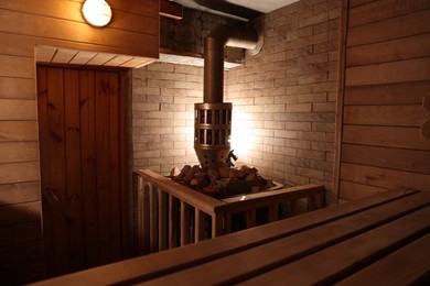 Photo of Wooden sauna with bench, stove and hot stones