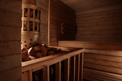 Photo of Wooden sauna with bench, stove and hot stones