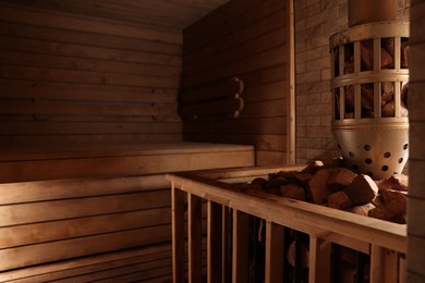 Photo of Wooden sauna with bench, stove and hot stones