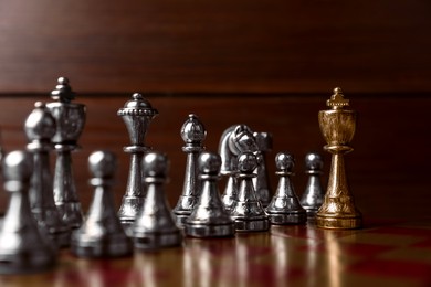 Photo of Golden chess king in front of other game pieces on chessboard. Competition concept