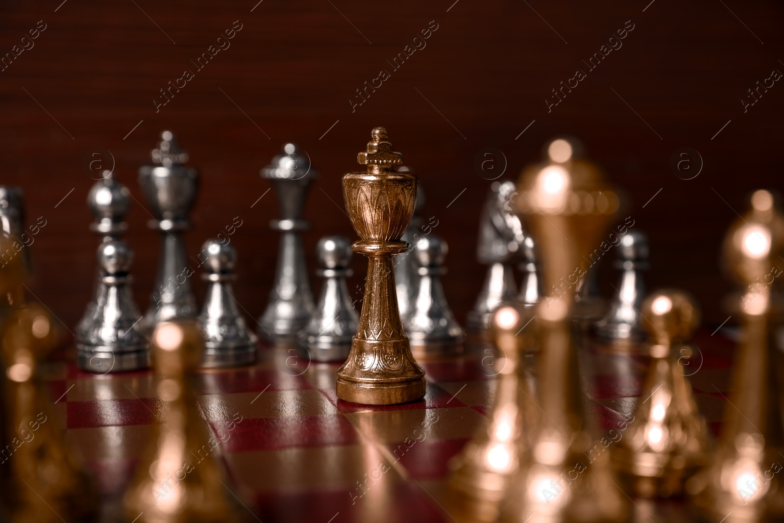 Photo of Golden chess king in middle of chessboard. Competition concept