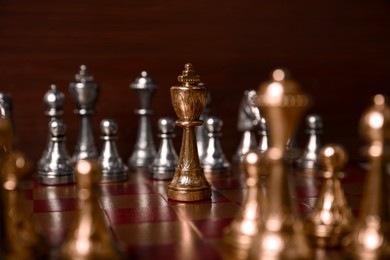 Photo of Golden chess king in middle of chessboard. Competition concept