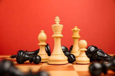 Photo of White chess pieces among other fallen black ones on chessboard, closeup. Competition concept