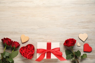 Photo of Romantic gift, roses, buds and decorative hearts on light wooden table, flat lay with space for text. Happy Valentine's day