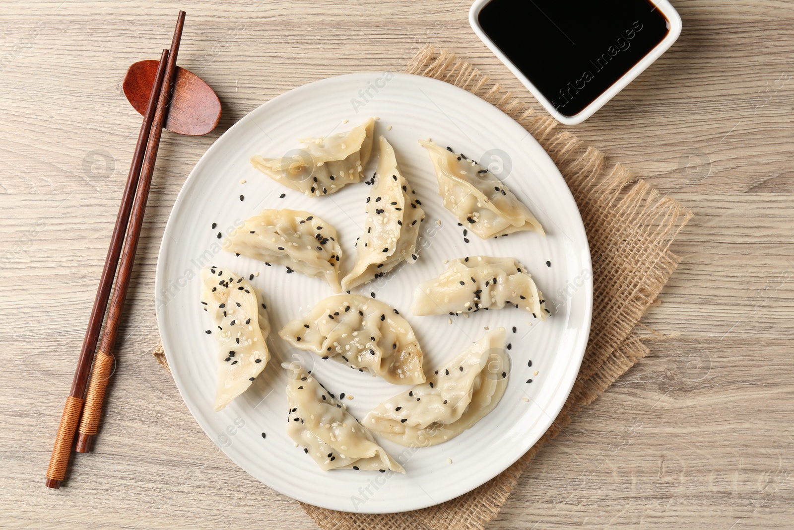 Photo of Delicious gyoza dumplings with sesame seeds served on wooden table, top view