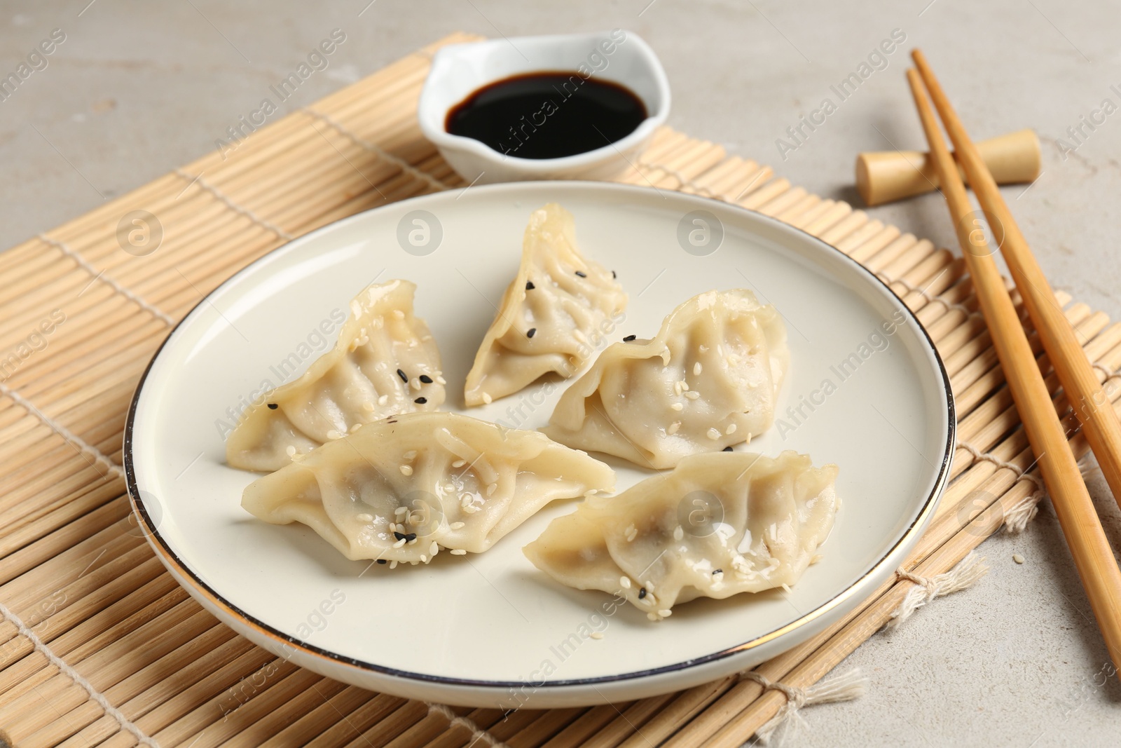 Photo of Delicious gyoza dumplings with sesame seeds served on light table, closeup