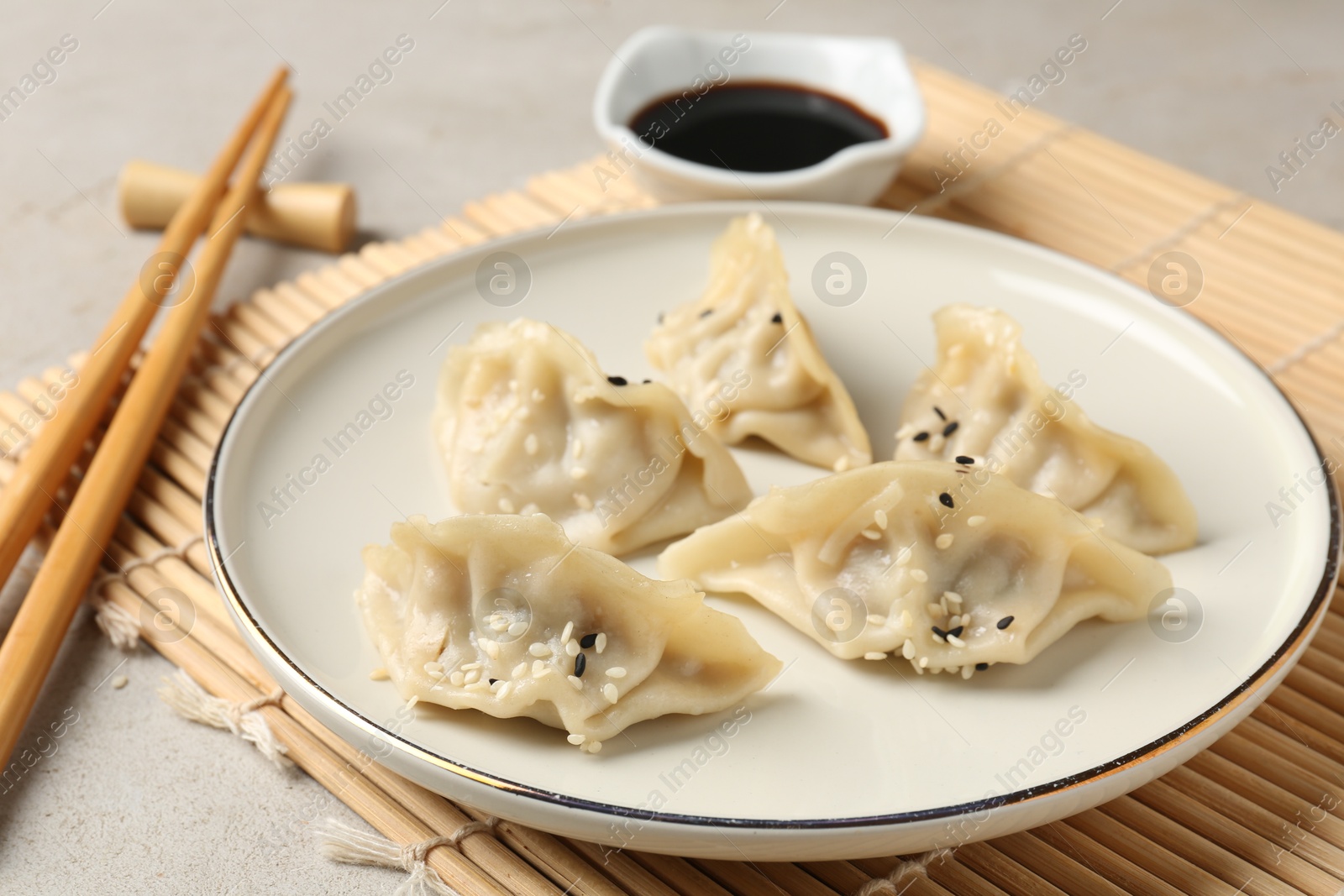 Photo of Delicious gyoza dumplings with sesame seeds served on light table, closeup