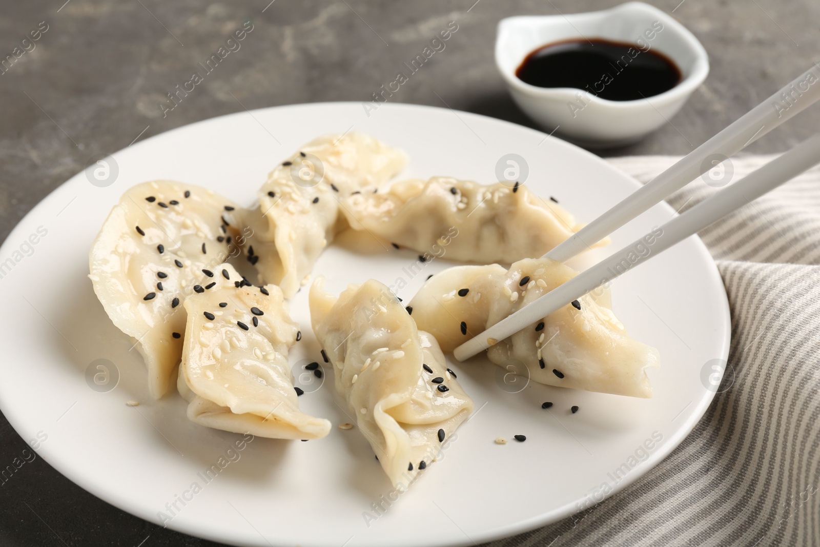 Photo of Eating tasty gyoza dumplings at grey table, closeup