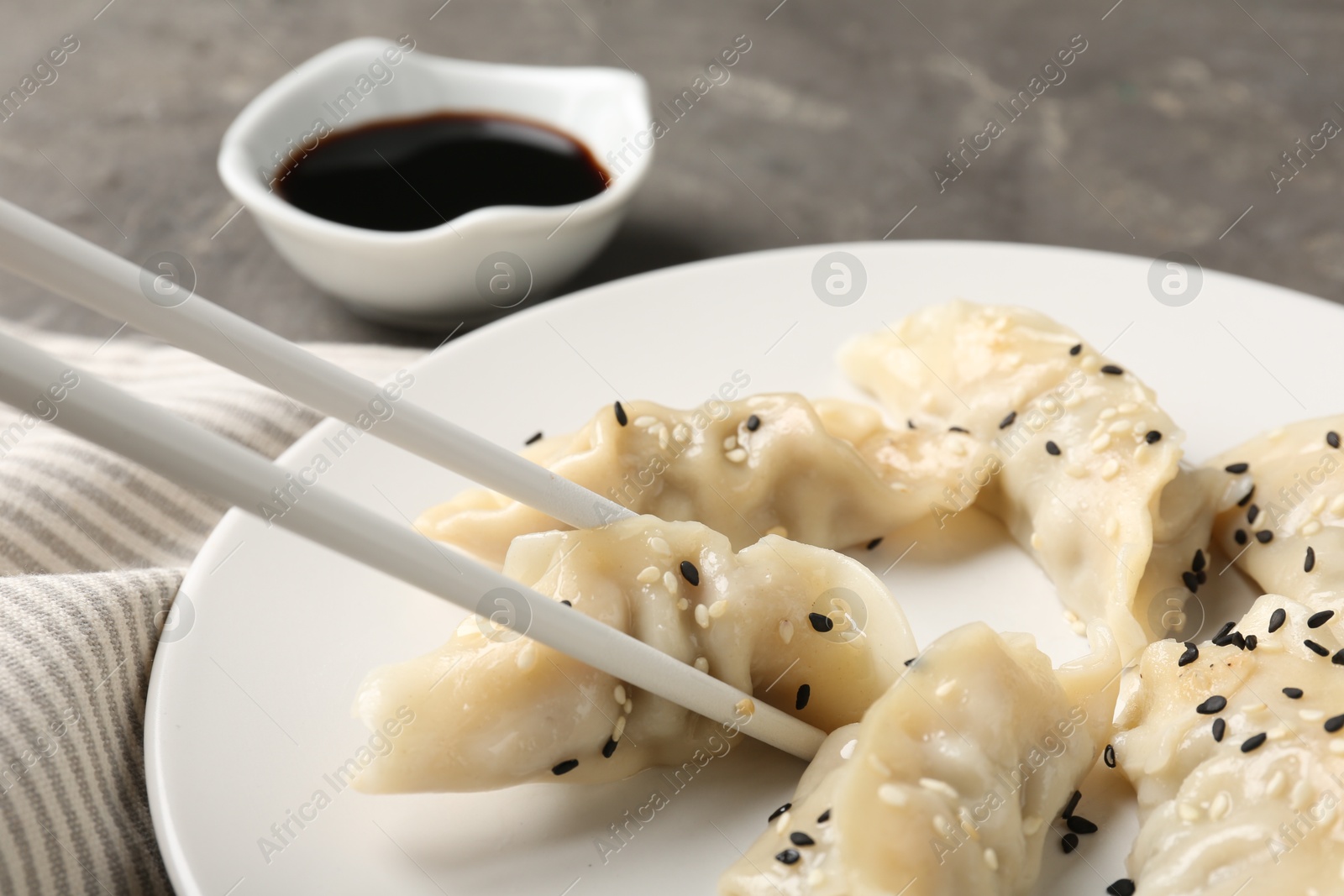 Photo of Eating tasty gyoza dumplings at grey table, closeup