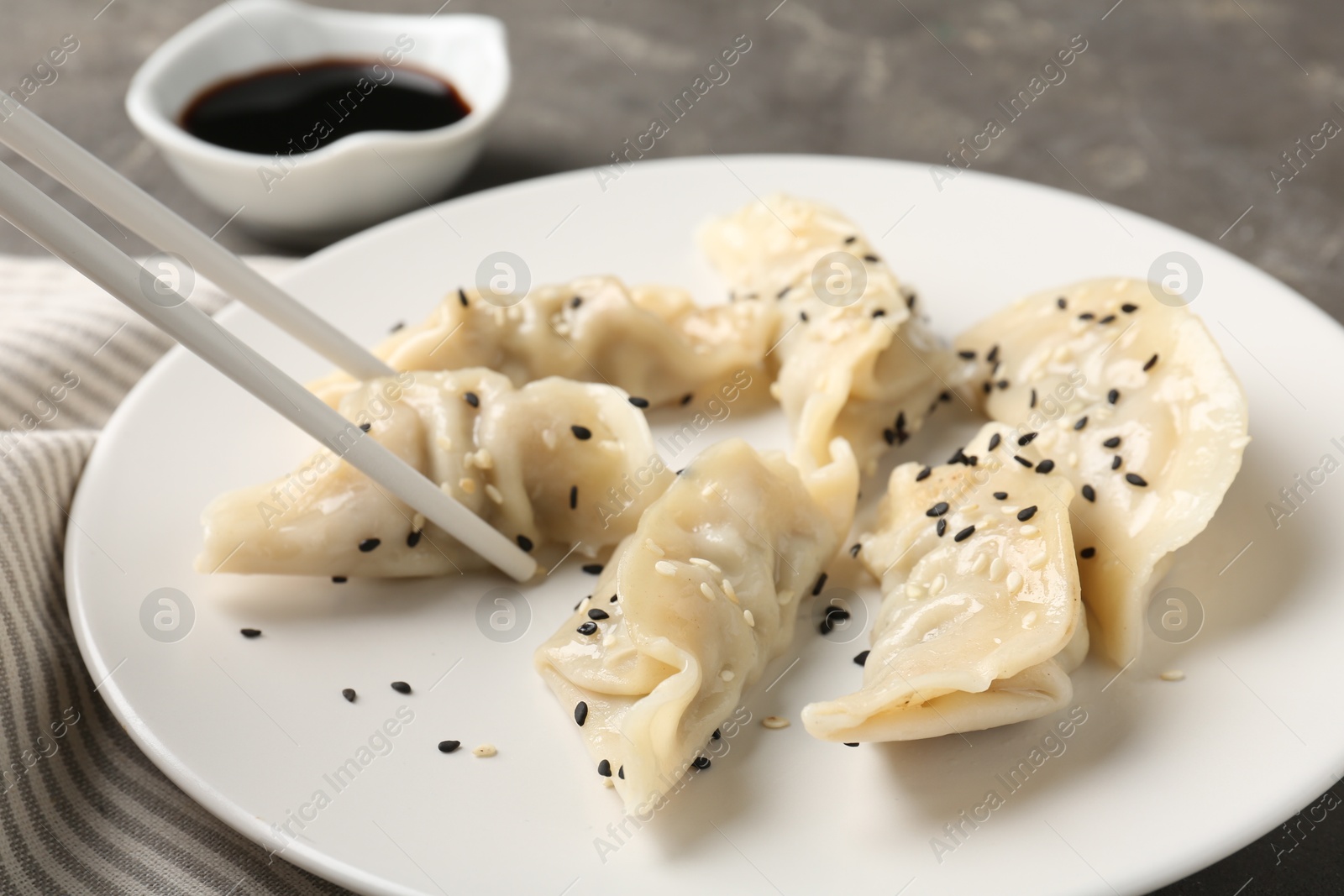 Photo of Eating tasty gyoza dumplings at grey table, closeup