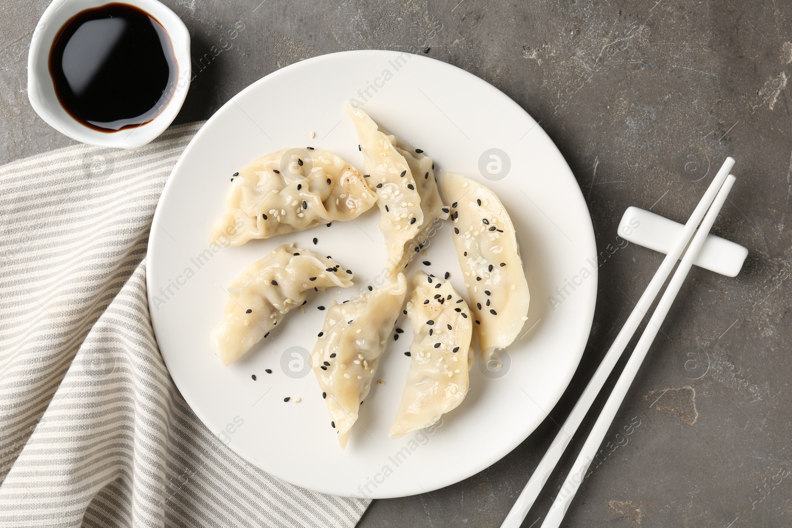 Photo of Delicious gyoza dumplings with sesame seeds served on grey table, top view