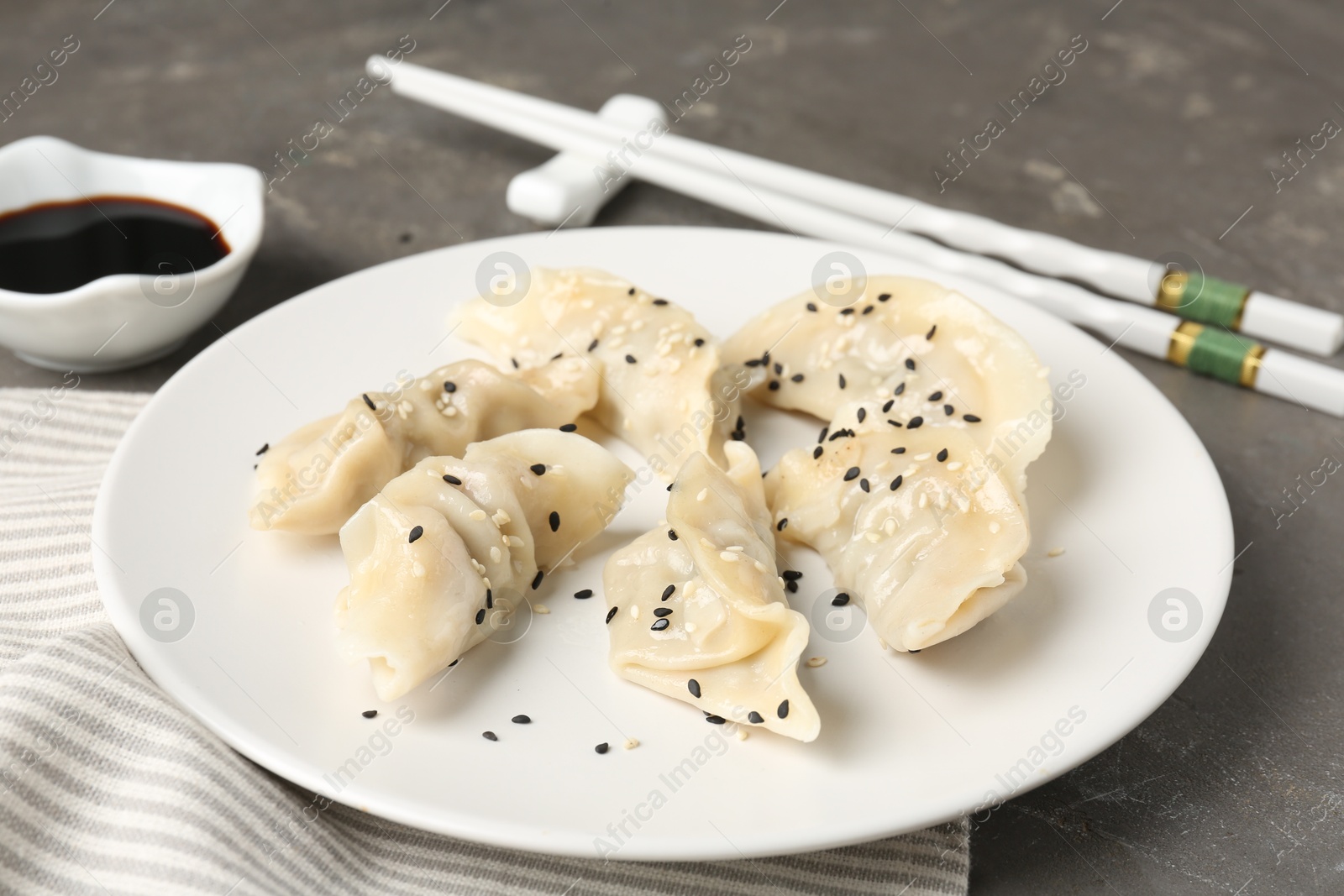 Photo of Delicious gyoza dumplings with sesame seeds served on grey table, closeup