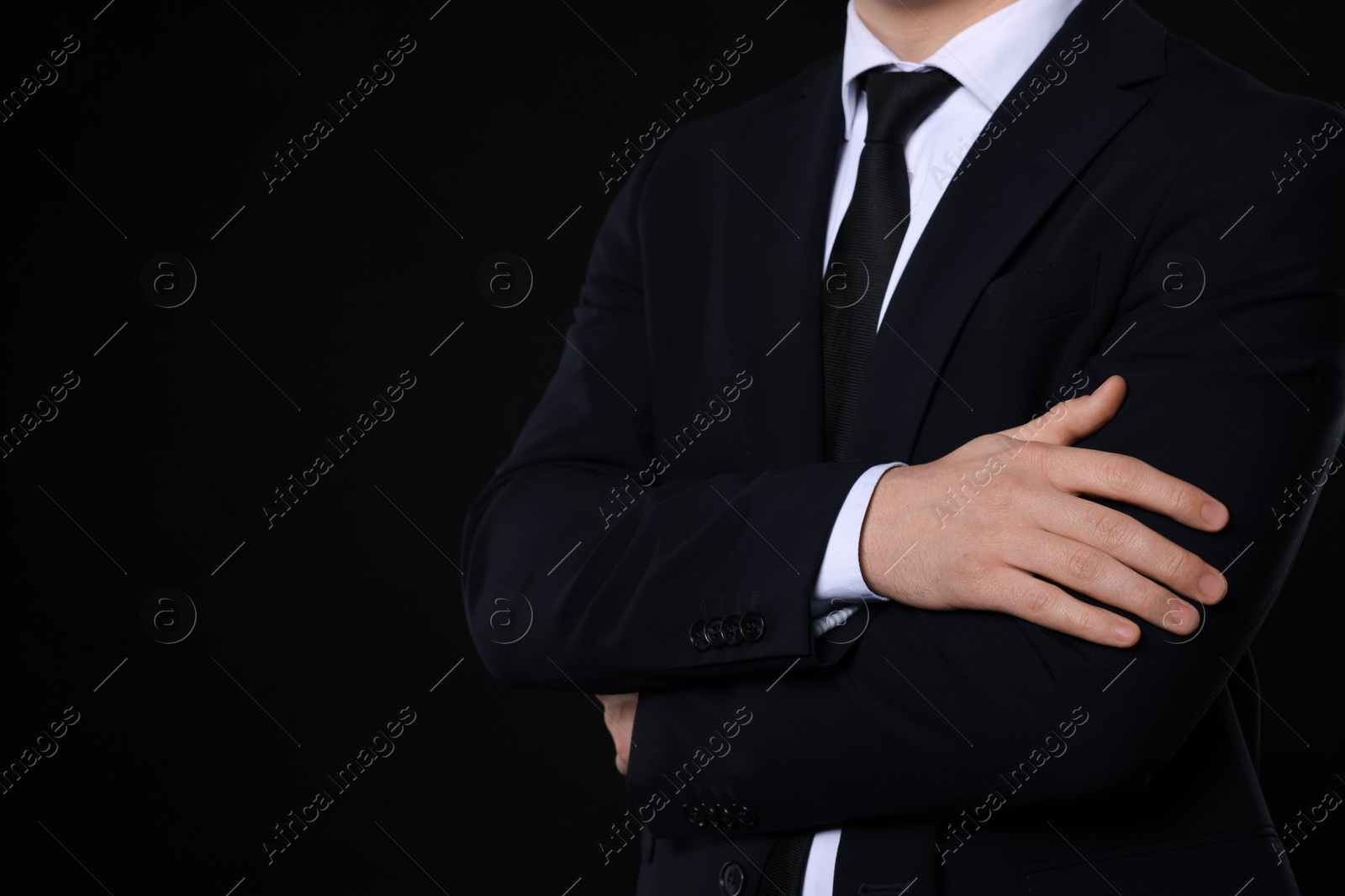 Photo of Man in classic suit on black background, closeup. Space for text