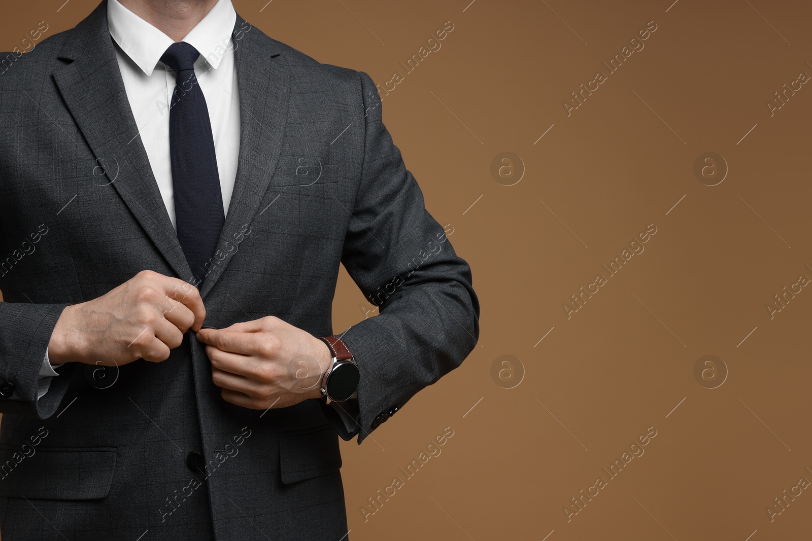 Photo of Man in classic suit on brown background, closeup. Space for text