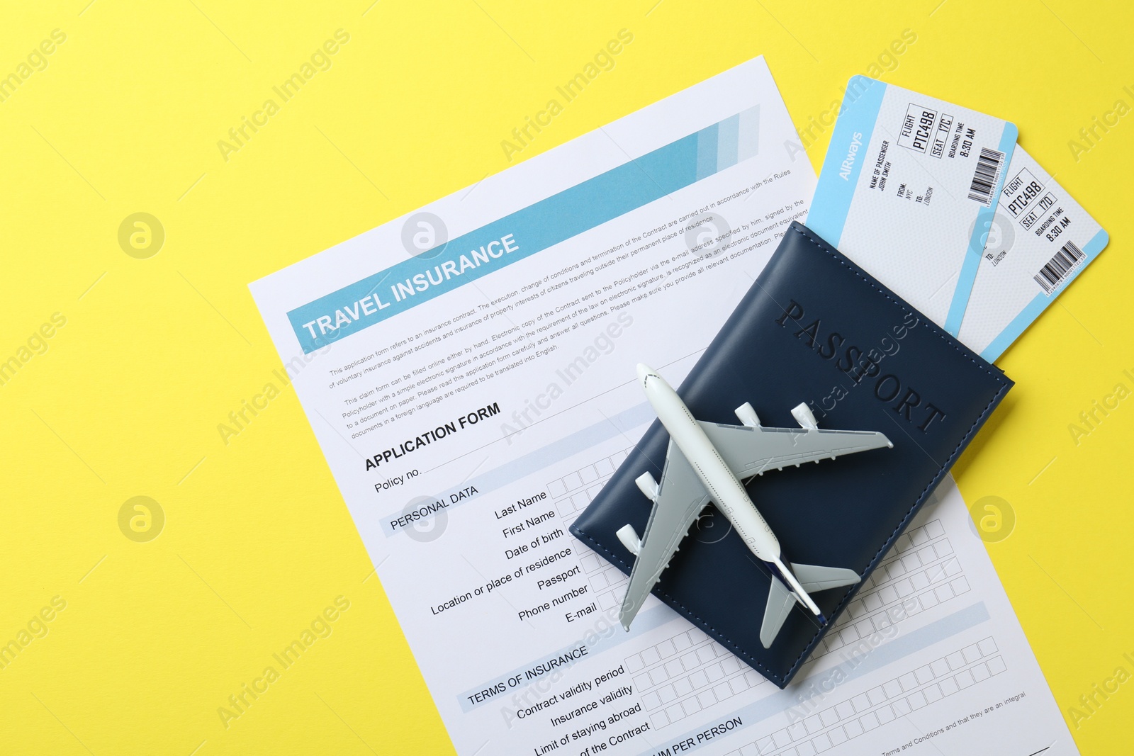 Photo of Medical tourism. Travel insurance application form, passport, flight tickets and plane model on yellow background, top view. Space for text