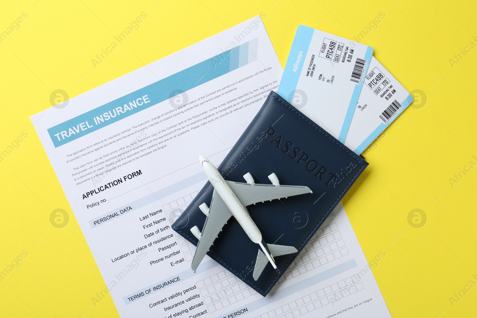 Photo of Medical tourism. Travel insurance application form, passport, flight tickets and plane model on yellow background, top view