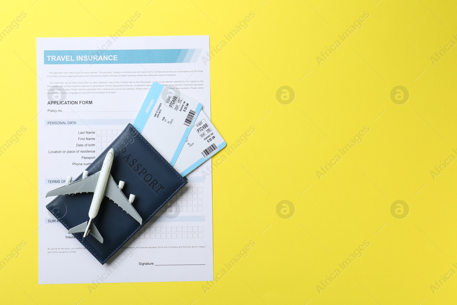 Photo of Medical tourism. Travel insurance application form, passport, flight tickets and plane model on yellow background, top view. Space for text