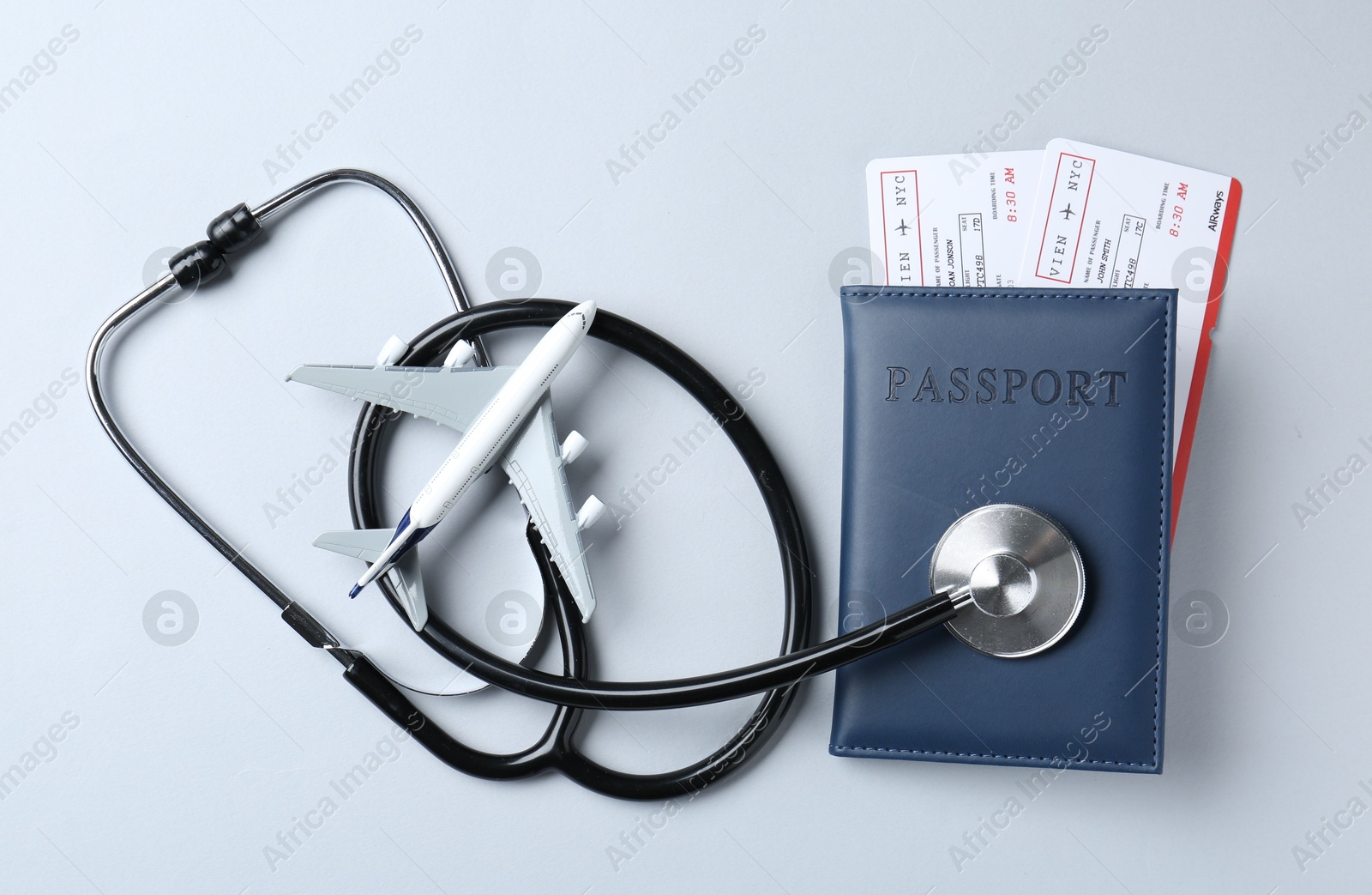 Photo of Medical tourism. Stethoscope and plane model on light grey background, flat lay