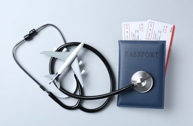 Photo of Medical tourism. Stethoscope and plane model on light grey background, flat lay