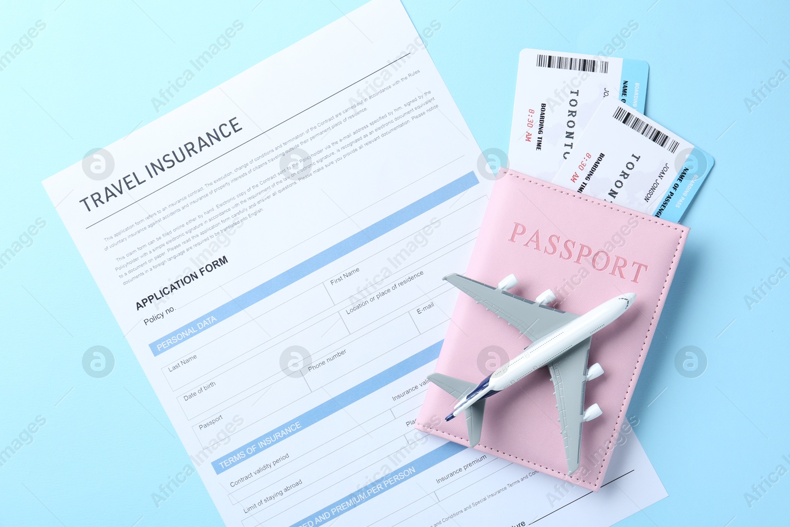 Photo of Medical tourism. Travel insurance application form, plane model, flight tickets and passport on light blue background, top view