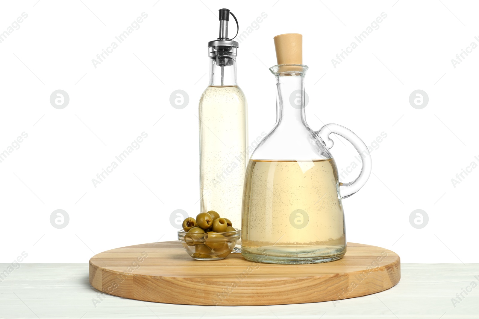 Photo of Vinegars in bottles and olives on wooden table against white background