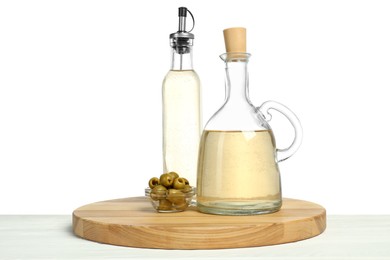 Photo of Vinegars in bottles and olives on wooden table against white background