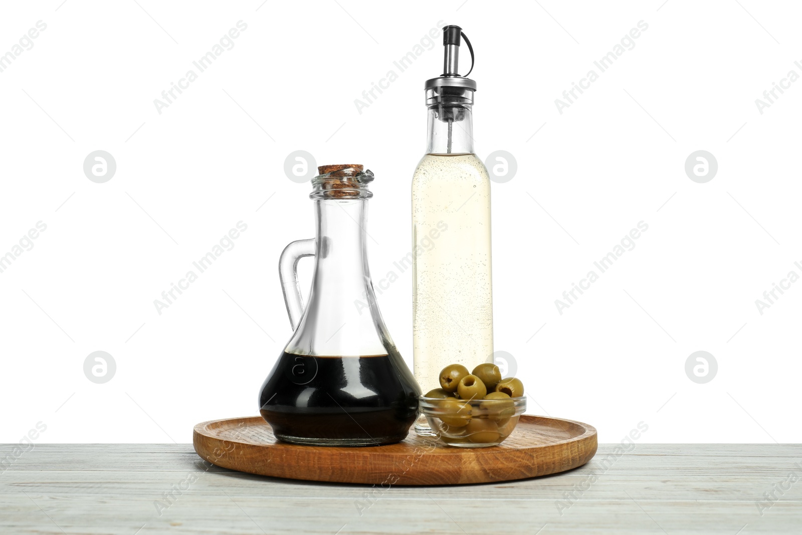 Photo of Vinegars in bottles and olives on wooden table against white background