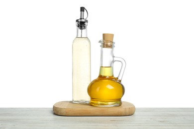 Photo of Oil and vinegar in bottles on wooden table against white background