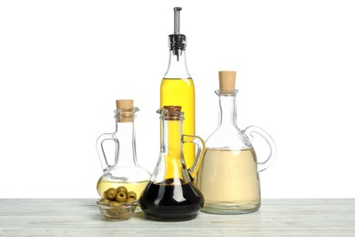 Photo of Salad dressings and olives on wooden table against white background