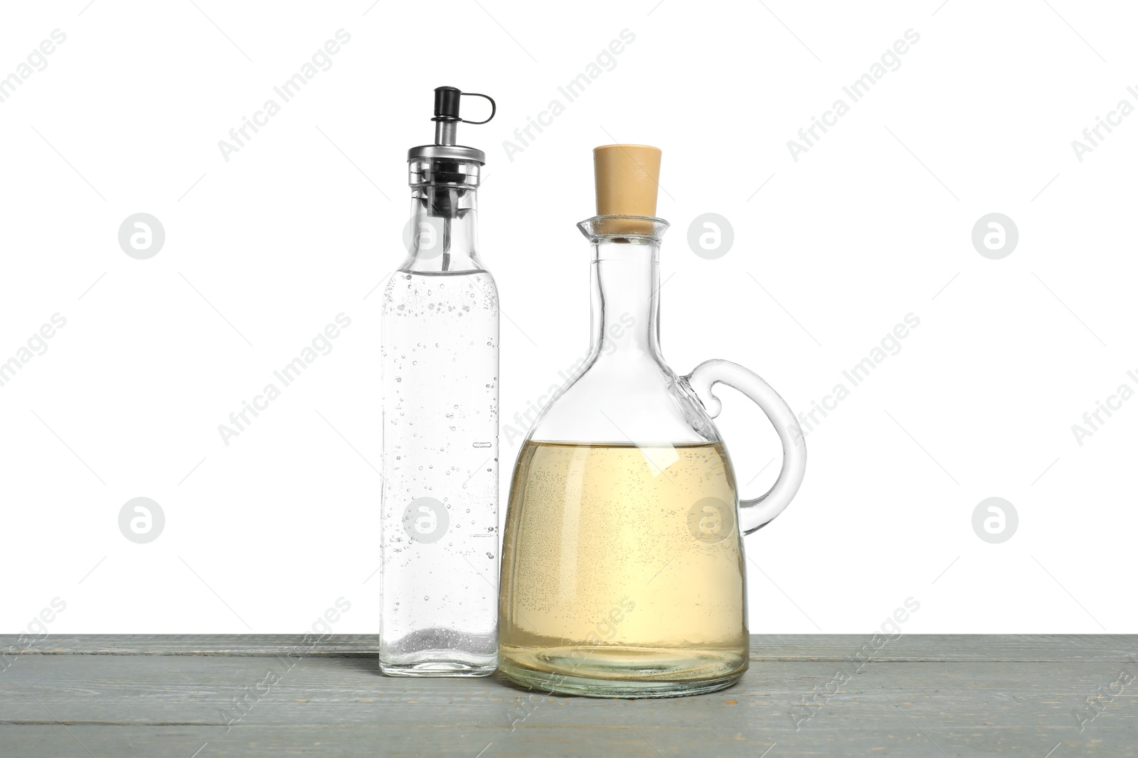 Photo of Vinegars in bottles on grey wooden table against white background