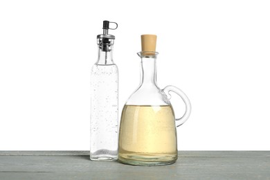 Photo of Vinegars in bottles on grey wooden table against white background