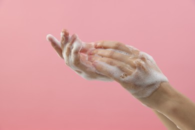 Photo of Woman washing hands with foaming soap on pink background, closeup. Hygiene