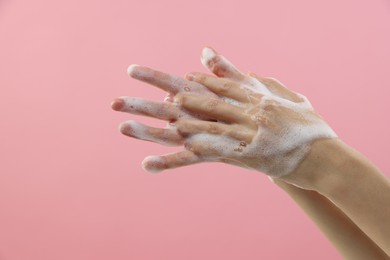 Photo of Woman washing hands with foaming soap on pink background, closeup with space for text. Hygiene