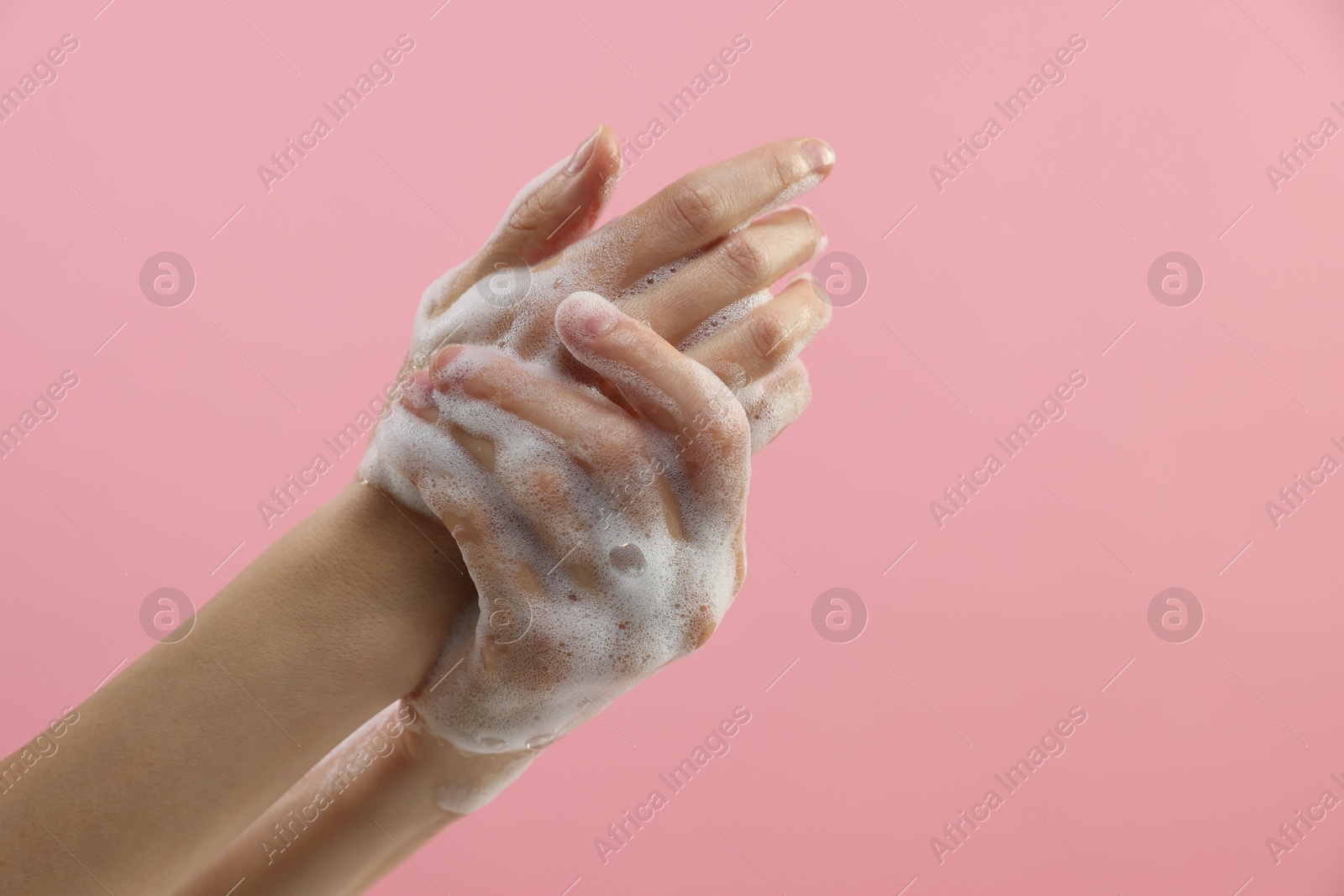 Photo of Woman washing hands with foaming soap on pink background, closeup with space for text. Hygiene