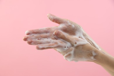 Photo of Woman washing hands with foaming soap on pink background, closeup. Hygiene