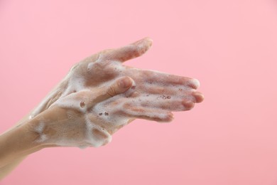 Photo of Woman washing hands with foaming soap on pink background, closeup. Hygiene