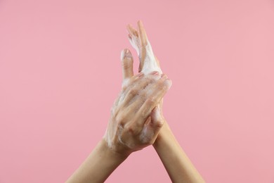 Photo of Woman washing hands with foaming soap on pink background, closeup. Hygiene