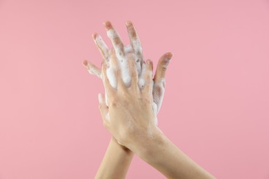 Photo of Woman washing hands with foaming soap on pink background, closeup. Hygiene