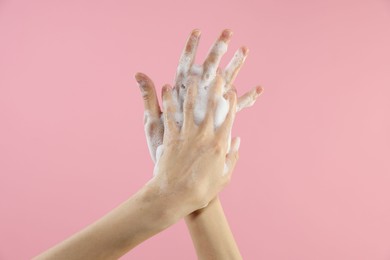 Photo of Woman washing hands with foaming soap on pink background, closeup. Hygiene