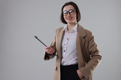 Portrait of young secretary with clipboard on grey background. Space for text