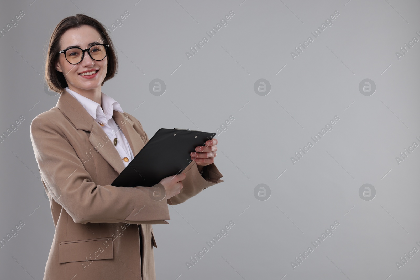 Photo of Portrait of young secretary with clipboard on grey background. Space for text