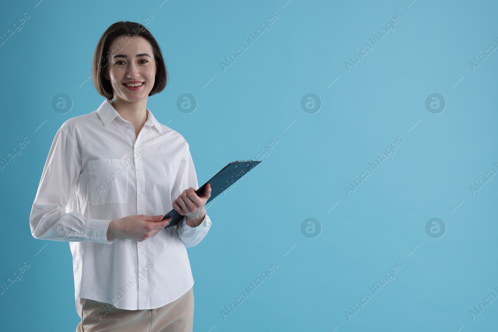 Photo of Portrait of young secretary with clipboard on light blue background. Space for text