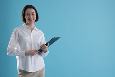 Photo of Portrait of young secretary with clipboard on light blue background. Space for text