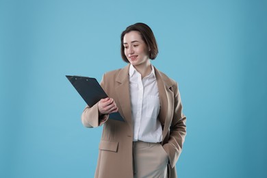 Photo of Portrait of young secretary with clipboard on light blue background