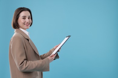 Photo of Portrait of young secretary with clipboard on light blue background. Space for text