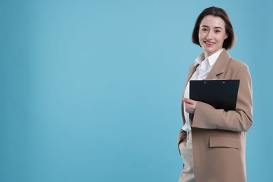 Portrait of young secretary with clipboard on light blue background. Space for text