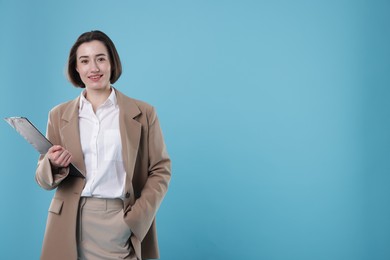 Photo of Portrait of young secretary with clipboard on light blue background. Space for text